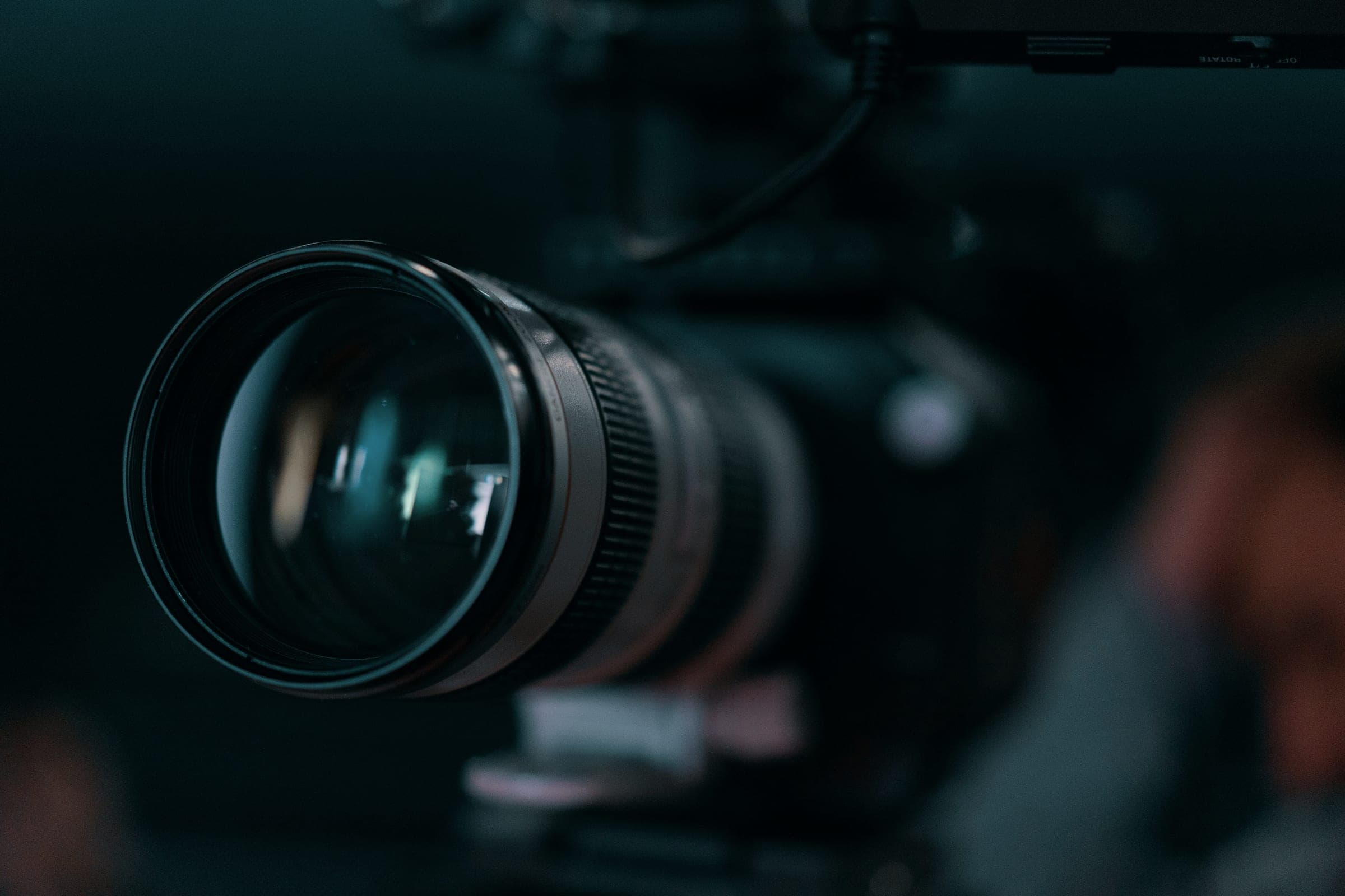 A close-up of a professional video camera lens in a dim studio.