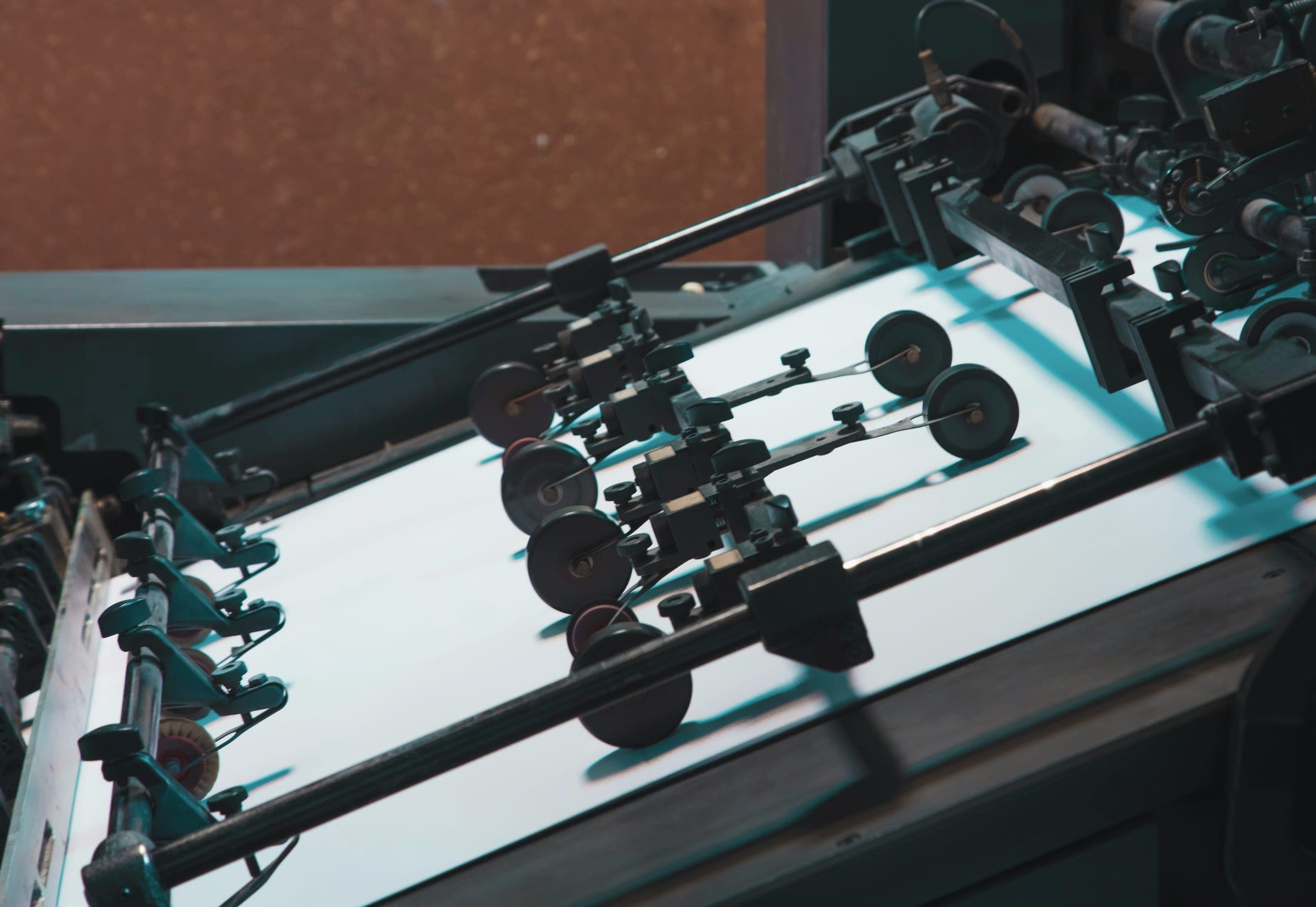 Rollers and guides of a printing press feeding a sheet of white paper.