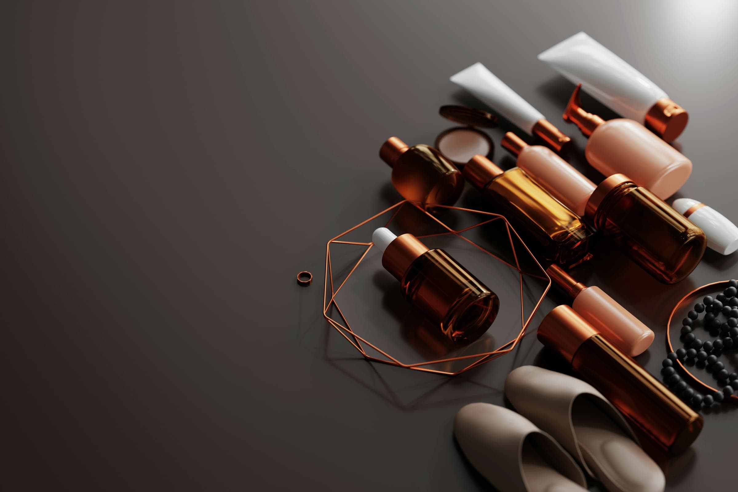 Unbranded amber glass bottles, white tubes and copper accents arranged on a dark brown surface.