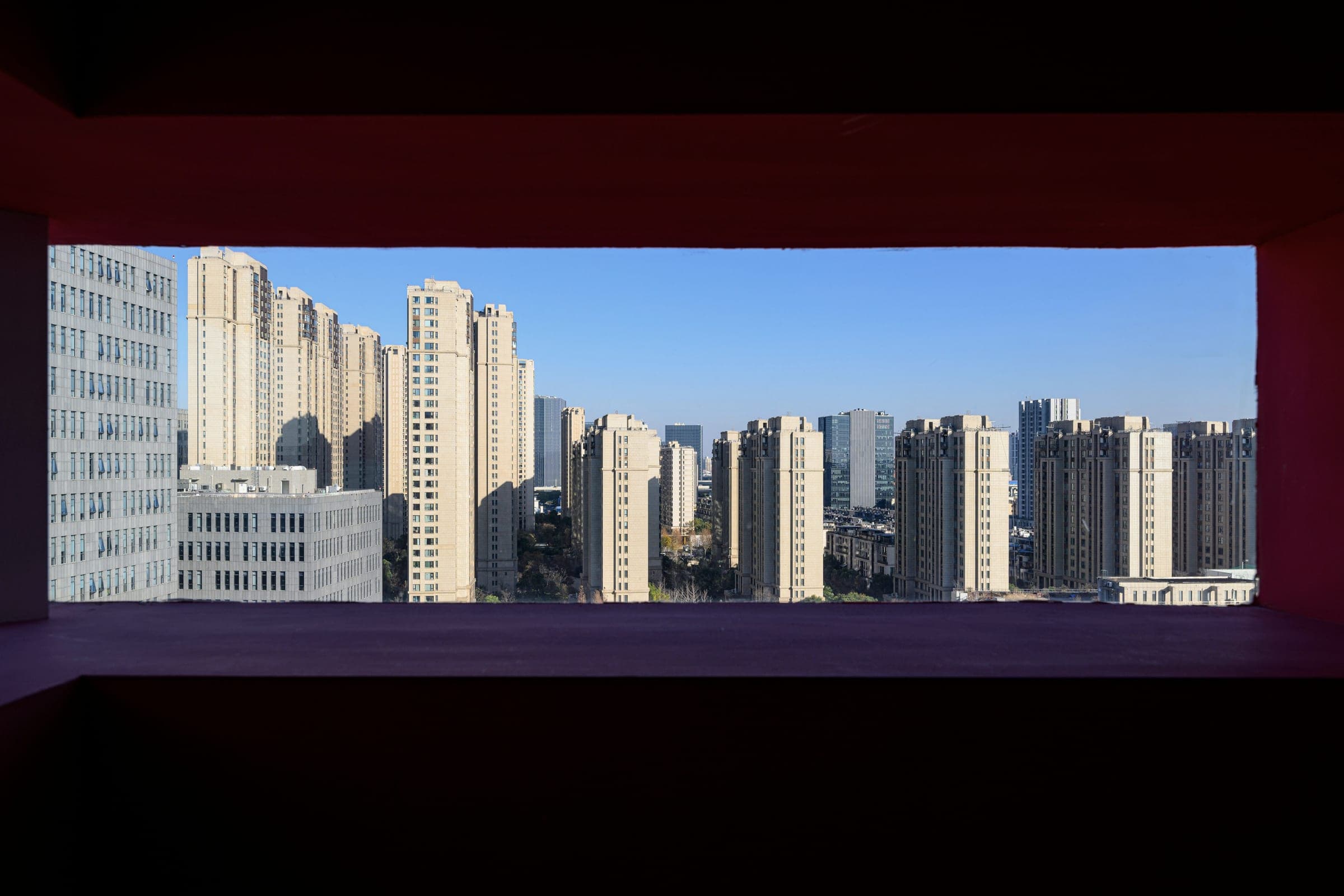 A view of high-rise residential towers framed by a dark rectangular opening.